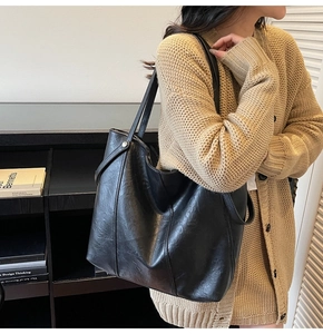 Vista laterale di una borsa tote nera in pelle con cuciture rinforzate e borchie decorative