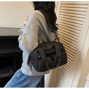 Detail of black nylon crossbody bag featuring multiple zipper pockets and wide shoulder strap