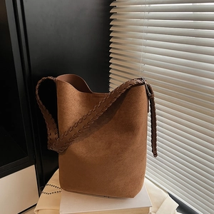 Detailed view of dark brown suede tote bag with woven stitching on the shoulder strap