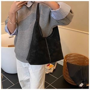 Detail of black suede tote bag featuring white contrast stitching and a single shoulder strap