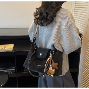 Detail of black tote bag with fashion tags and bear charms in a cozy indoor setting