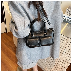 Black glossy crossbody pillow bag with dual front flap pockets worn by a model