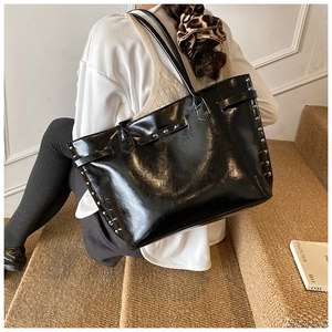 Detailed view of a black tote bag with silver studs on a stylish urban background