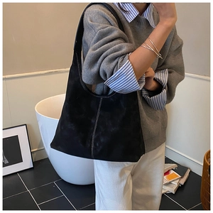 Detail of black suede tote bag featuring distinctive white contrast stitching and minimalist style