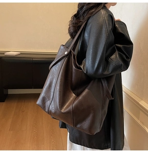 Vista dettagliata della borsa tote in pelle marrone scuro con trama fine e fibbia laterale