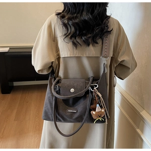 Deep brown matte tote bag with geometric jacquard strap and plush bear charm on model