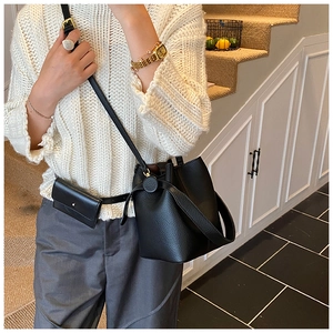 Detailed view of black pebbled leather bucket bag with matching mini pouch and slim strap