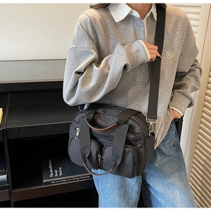Detail view of black nylon crossbody bag with multi-pocket design and brown handles