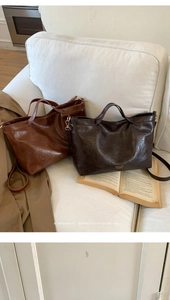 Detail of retro oil wax leather tote bags with brand logo on a cozy home sofa setting