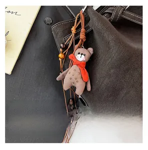 Detail of cute brown plush bear charm with red scarf and wooden beads on tote bag