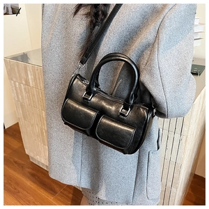 Detail of black leather handbag with dual front flap pockets and silver metal buckles