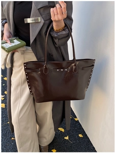 Detail of dark brown tote bag with metal studs and slender shoulder straps