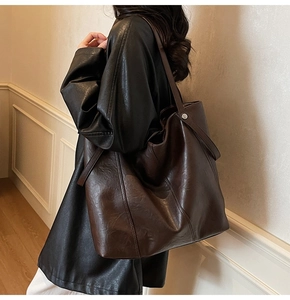 Dettaglio della borsa tote marrone scuro con cuciture decorative e rivetti in metallo