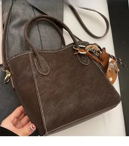 Detail der dunkelbraunen Leder-Eimertasche mit weißen Kontrastnähten und Goldbeschlägen