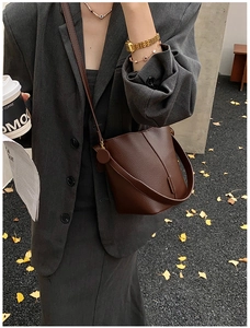 Detail of dark brown leather bucket bag with litchi grain texture for office commuting