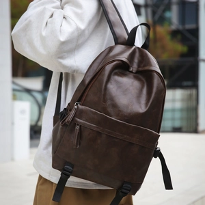 Detailed view of the dark brown leather backpack showing texture and front pocket