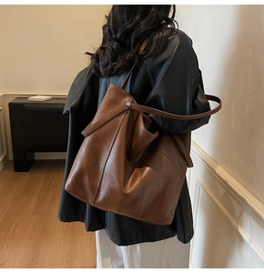 Dettaglio di una grande borsa tote marrone con pelle testurizzata e rivetti in metallo