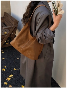 Detail of a brown vintage tote bag in suede texture with stylish white stitching