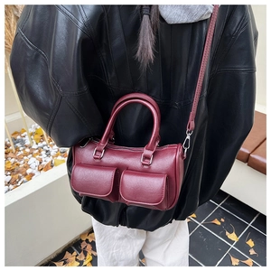 Detail view of burgundy crossbody barrel bag with pockets shown on a stylish model