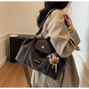 Detail of dark brown matte tote bag featuring a cute bear charm and patterned strap