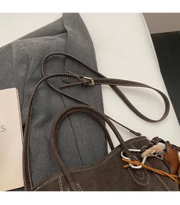 Detail der dunkelbraunen Wildleder-Beuteltasche mit Kontrastnähten und goldener Schnalle