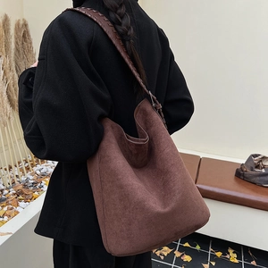Brown suede hobo tote bag featuring a woven leather strap shown on a model in autumn