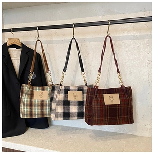 Three plaid tweed tote bags in various colors hanging on a rack with a black blazer