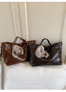 Detail of retro oil wax leather tote bags with plush bunny charms on a soft white sofa