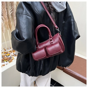 Detail of burgundy leather Boston bag with double front flap pockets and adjustable strap