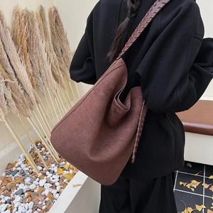 Close-up of brown suede tote bag featuring bohemian braided strap and matte texture