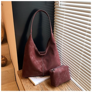 Detail of burgundy faux suede tote bag set with small matching zipper pouch on wood