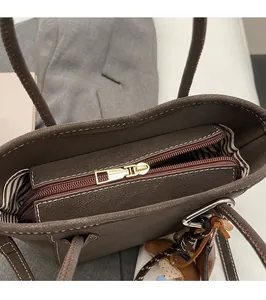Nahaufnahme von Reißverschluss und gestreiftem Futter der braunen Beuteltasche aus Leder
