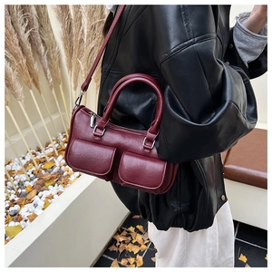 Detail of burgundy Boston handbag with multiple pockets on a stylish street-style model
