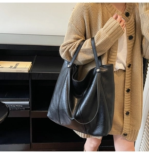 Dettaglio di borsa tote in pelle nera con rivetti argentati e doppie tracolle sottili