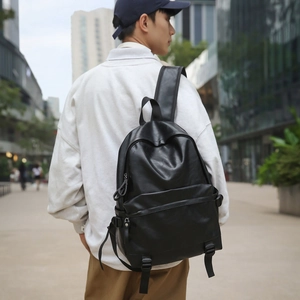 Close-up of minimalist black leather backpack with adjustable straps and front zipper pocket