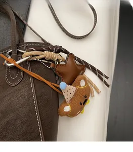 Detail von Plüschbär und Lederstern-Anhängern an einer braunen Beuteltasche mit Kieselleder