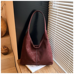 Detail view of burgundy faux suede tote bag with elegant shadow lighting on matte surface