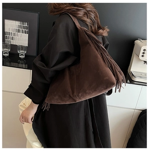 Detail of vintage brown suede tote bag with long tassels shown on shoulder