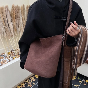 Detail of a brown faux suede tote bag featuring a thick woven strap and matte texture