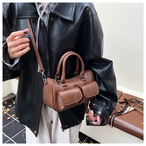 Close-up of a vintage brown leather satchel bag featuring two functional front flap pockets