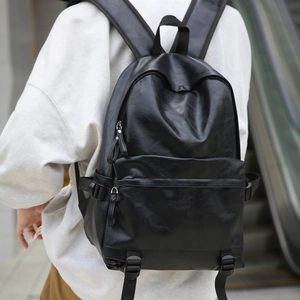 Detail of minimalist black soft leather backpack with textured finish and side strap