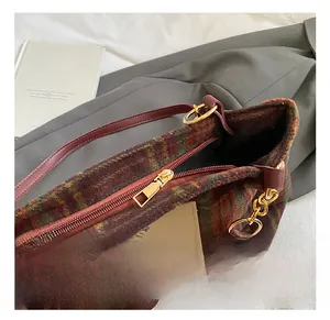 Detailed close-up of golden metal zipper and bear patch on plaid wool tote bag