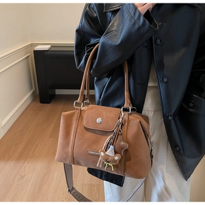 Detail of vintage brown tote with geometric woven strap and plush pendant accessory