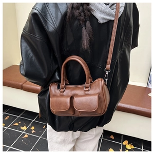 Detail view of a brown vintage Boston bag with dual flap pockets and top handles