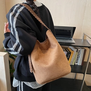 Brown faux suede hobo bag with woven strap shown on model in a modern office setting