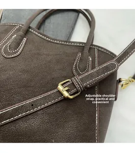 Nahaufnahme braune Leder-Eimertasche mit weißen Nähten und goldener verstellbarer Schnalle
