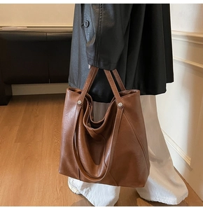 Dettaglio della borsa tote marrone caramello con fibbie in metallo argentato e pelle PU opaca