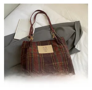 Detail showing red and brown plaid tote bag texture with cute bear patch detail