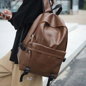 Detailed close-up of brown PU leather texture and durable zippers on a retro backpack