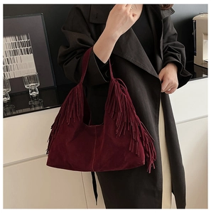 Close-up of burgundy frosted suede tote bag with long tassels on a fashion model